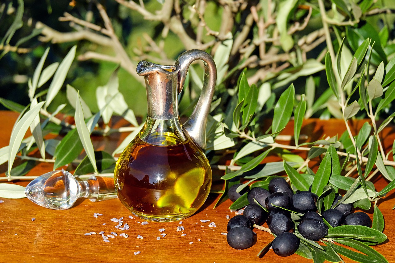 Dzbanek oliwy i oliwki na stole w ogrodzie